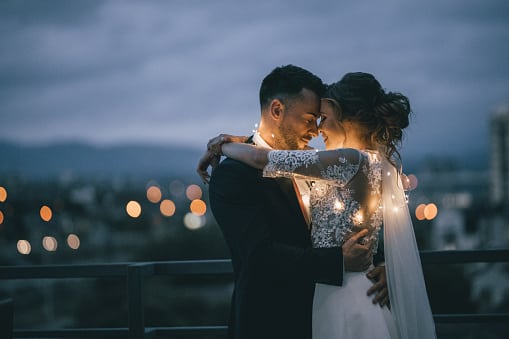 Romantic newlyde couple standing on the roof top in the city in the night